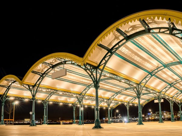 An angled shot of three yellow curved roofs in a city with lights under a dark sky